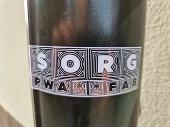 Black and white sticker with a geometric design. Each letter of the text is inside a square with a geometric pattern. The text is $ORG PWA*FAB.