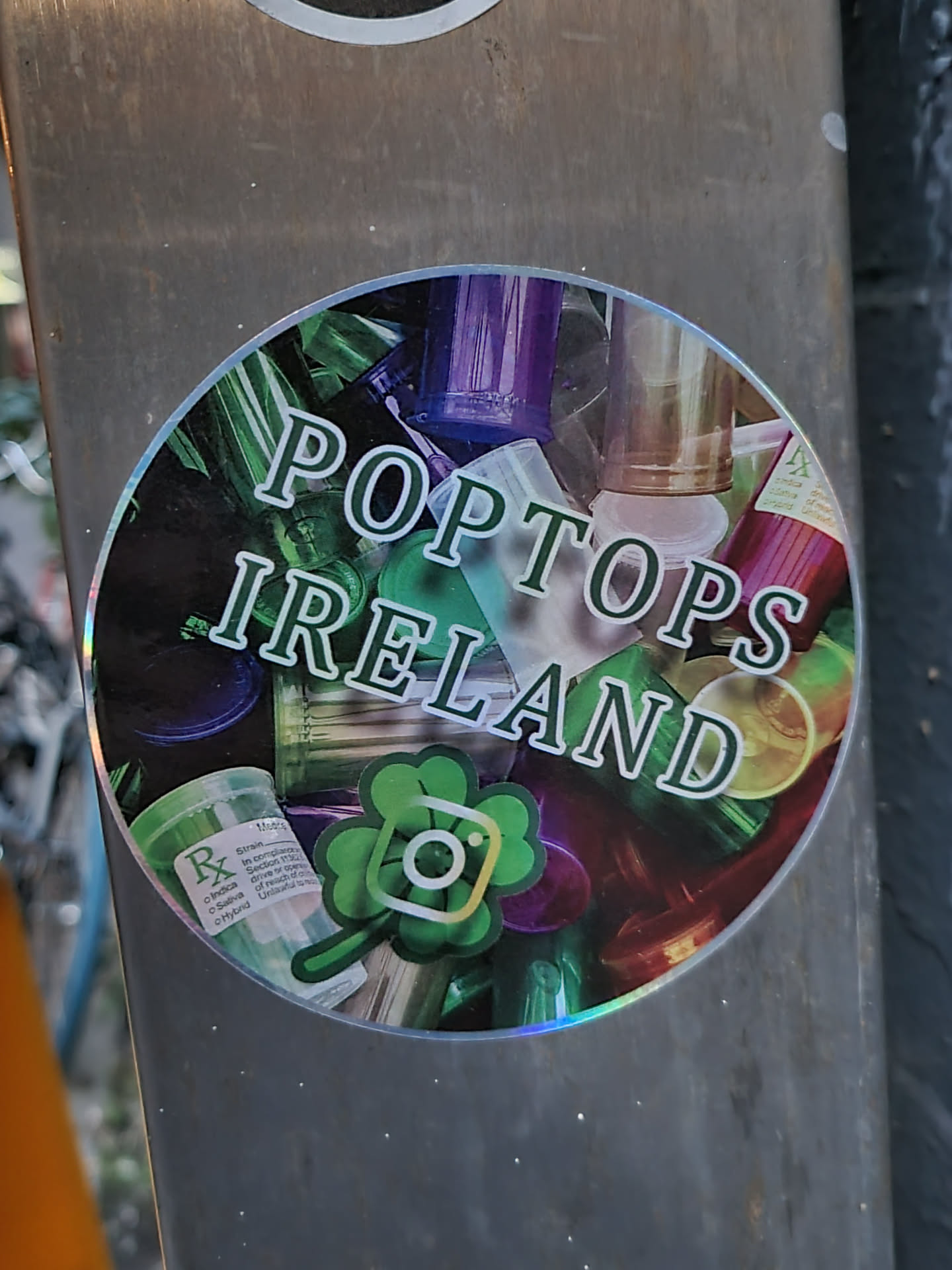 A round sticker featuring a design of various pop tops with the text "POPTOPS IRELAND" written on it.  There's also a small shamrock with an Instagram logo inside it on the bottom of the sticker.