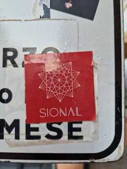 A red square sticker with a white geometric design resembling a star. The word SIONAL is printed in white beneath the design.