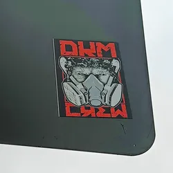 A sticker featuring a grayscale image of a person wearing a gas mask, with the text "DM CREW" in red on a black background.