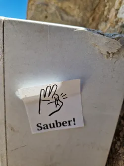 A sticker with a hand gesture and the word "Sauber!" (Clean!) in German.  The hand gesture symbolizes cleanliness or approval.