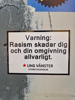 A sticker warning against racism.  It's in Swedish and states that racism seriously harms you and those around you.  The sticker is from Ung Vänster Storstockholm (Young Left Stockholm).