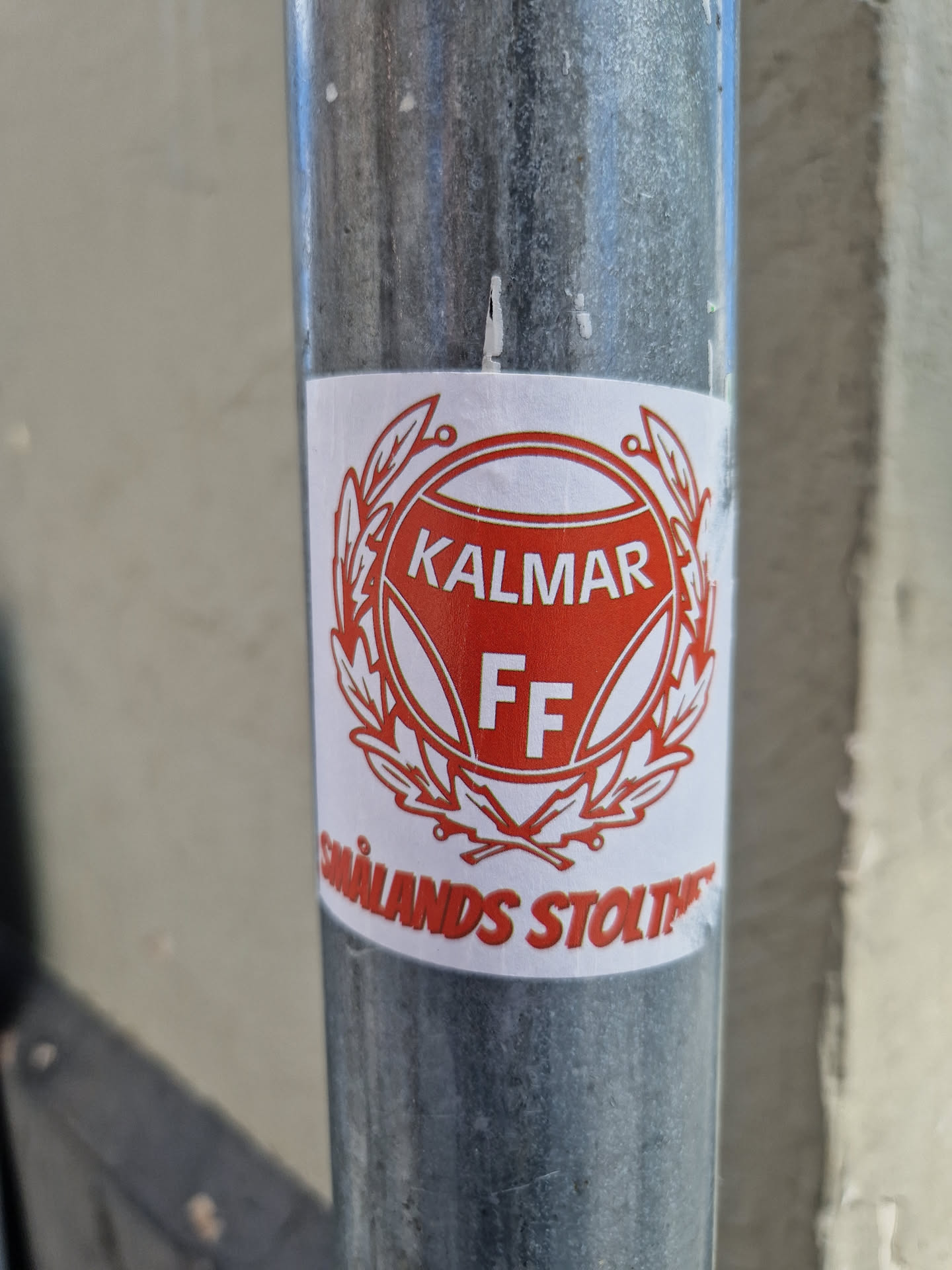 A sticker featuring the logo of Kalmar FF, a Swedish football club. The logo is a red and white crest with the words "KALMAR FF" written in the center.  The sticker also features the text "Smålands stolthet" which translates to "The pride of Småland".