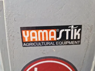 A sticker featuring the Yamastik logo and the words 'Agricultural Equipment'. The sticker is rectangular with a black background, orange text, and a white outline. The logo includes a stylized depiction of a farming tool or implement.