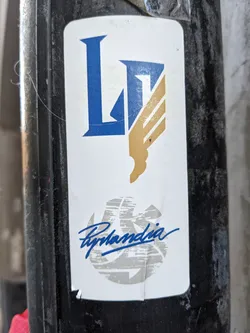 A white sticker with a blue and gold logo that says LP and a grey circle with the signature Ryhandia. 