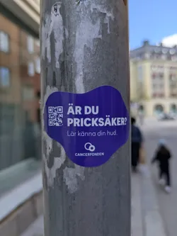 This sticker is promoting awareness about skin cancer. The text "ÄR DU PRICKSÄKER?" translates to "Are you spot safe?" or "Are you prick safe?" in English, with "prick" referring to moles or skin spots. The text "Lär känna din hud" means "Get to know your skin."