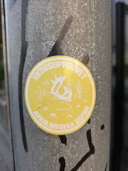 Yellow round sticker with a reindeer illustration and text in Swedish.  The text translates to "Forest Uprising: Decolonize Sapmi".