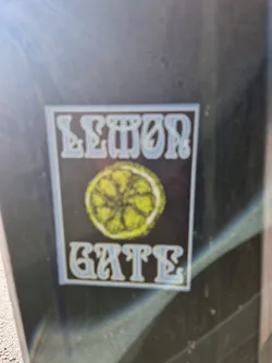 A sticker with the words "Lemon Gate" in a stylized font, accompanied by a graphic of a lemon slice. The sticker has a black background with light blue text.
