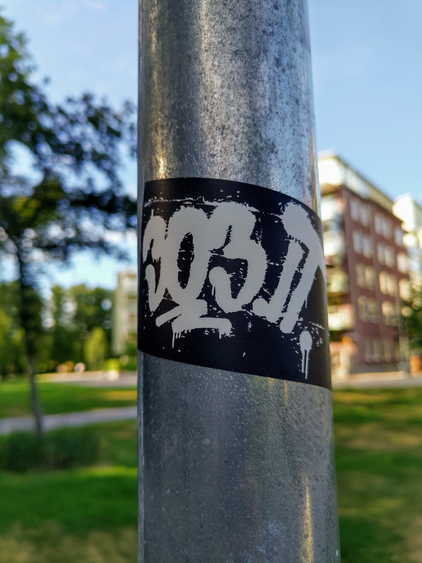 A black and white sticker with the number 30317 stylized in graffiti lettering. It's been placed on a metallic lamppost outside, suggesting street art culture. 