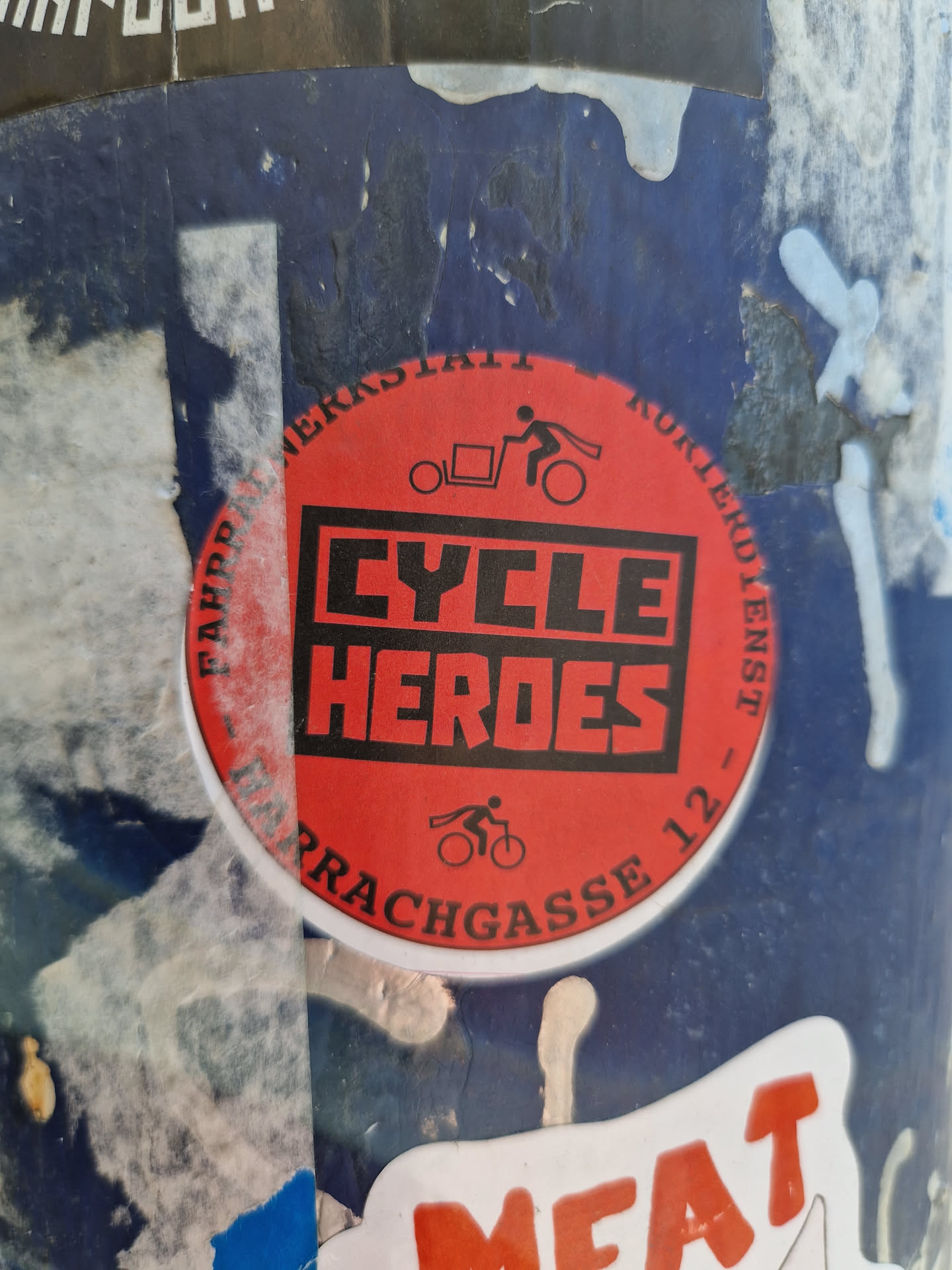Red and black circular sticker with the text "CYCLE HEROES" in bold letters. It also contains a small illustration of a person riding a bicycle with a cargo trailer. The text around the circle seems to indicate a location or address: "FAPPER MERKERSTAATT KURIERDIENST - ULRACHGASSE 12"