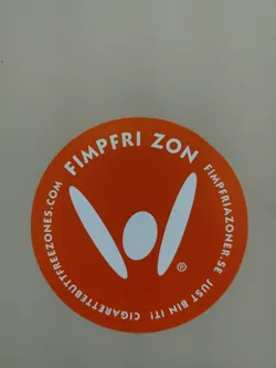 Street sticker Orange circular sticker with a logo and text indicating a cigarette bin and a website. The logo depicts a stylized figure with raised arms.