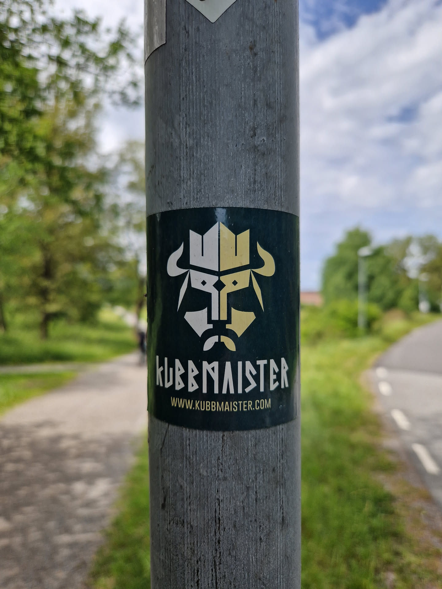 A dark green sticker with a minimalist design featuring a stylized bull's head and the text "KUBBMAISTER" and website address. The logo appears to represent a combination of Viking and Kubb imagery.