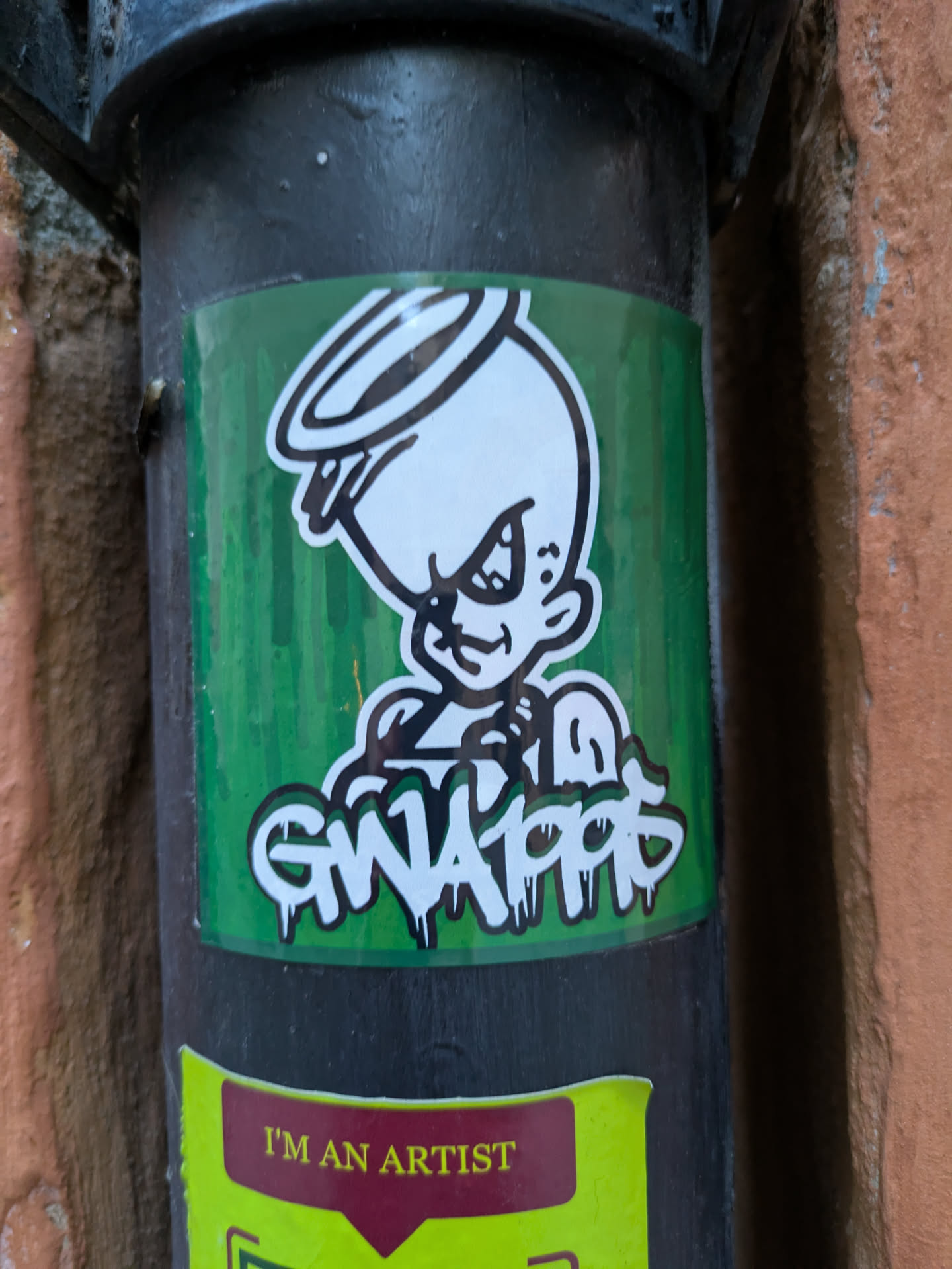 A sticker featuring an illustration of a GWA10PP character. The character has a halo and a mischievous expression. The sticker is on a dark-colored pipe.