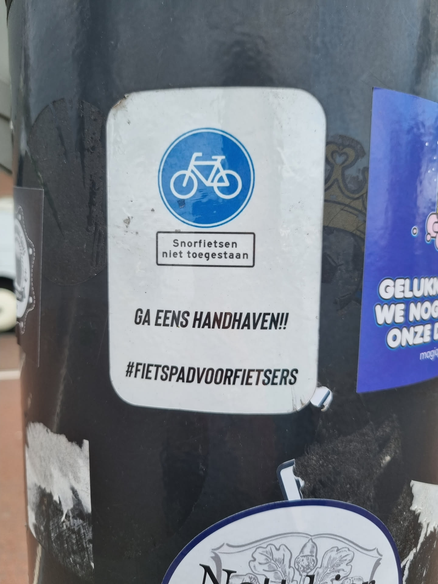 A sticker advocating for bicycle paths to be used only by cyclists. It features a bicycle symbol and the text 'Snurf fietsen niet toegestaan' (Motorized bicycles not allowed) and a call to action to enforce this rule. 