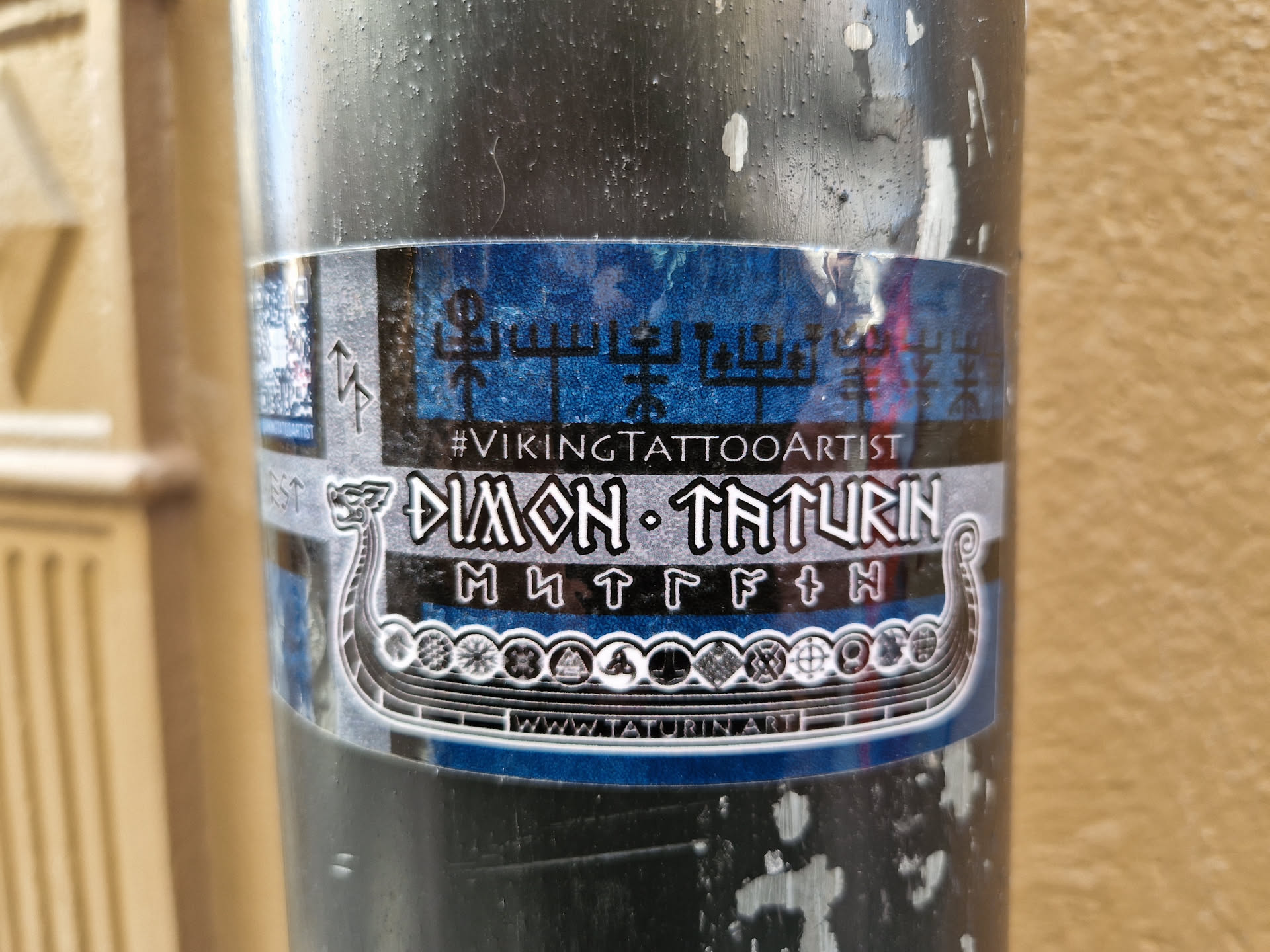 Sticker featuring a Viking ship, runes, and the artist's name and tagline. The design is predominantly blue and silver with black details.