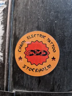 Round sticker with the text "Chain Electric Tattoo" and a logo of three linked chains forming a circle. The words "Stockholm" are written under the main text.