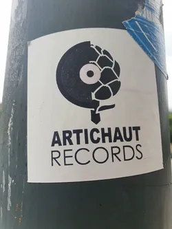 A white sticker featuring a black and white design.  Half of the design is a vinyl record and the other half is an artichoke. Below the design, the text 'ARTICHAUT RECORDS' is written in a sans-serif font. 