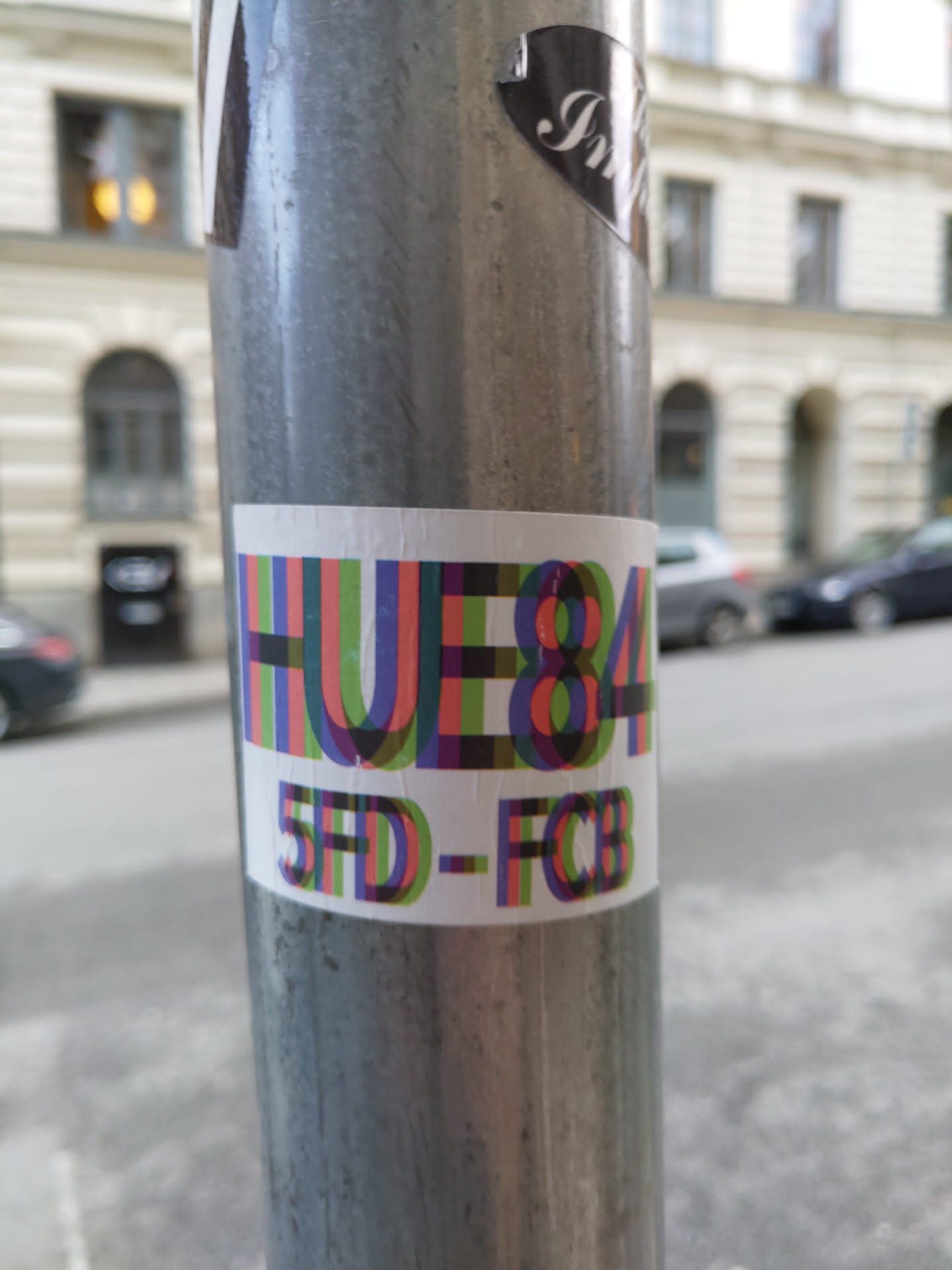 A colorful sticker with the text HUE84 and 5FD-FCB. The text is stylized with overlapping letters in various colors.