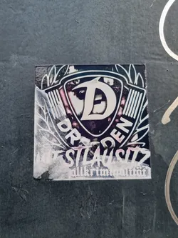 A sticker featuring a stylized 'D' inside a shield-like emblem with wings, the words 'DRESDEN' and 'NEUSTADT' flanking it and 'allkriminalität' at the bottom.