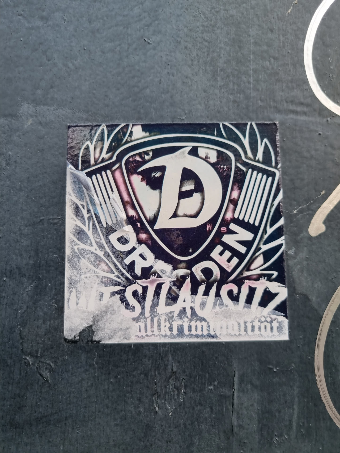 A sticker featuring a stylized 'D' inside a shield-like emblem with wings, the words 'DRESDEN' and 'NEUSTADT' flanking it and 'allkriminalität' at the bottom.