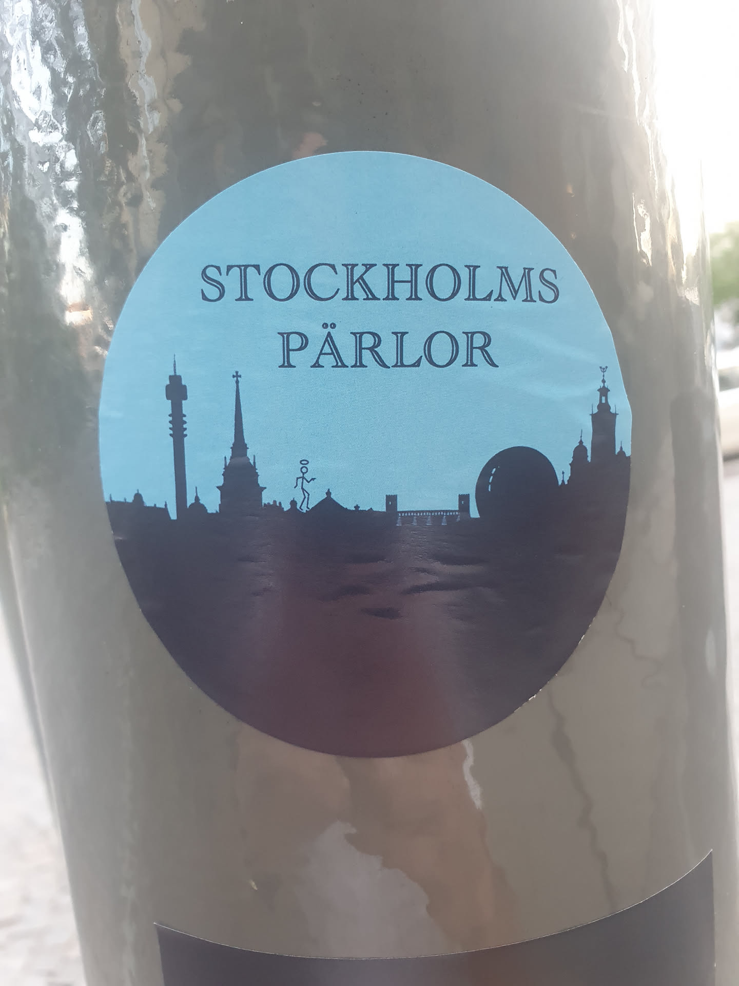 A round sticker featuring a silhouette of the Stockholm skyline on a light blue background. The text "STOCKHOLMS PÄRLOR" is written in a serif font at the top.