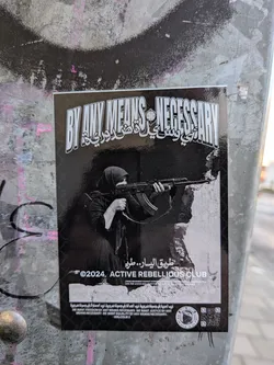 The sticker features a black and white image with a prominent title in bold, stylized English lettering that reads 'BY ANY MEANS NECESSARY'. Below this, in Arabic script, is text that appears to be a translation or related phrase. The central image depicts a woman wearing a hijab, holding and aiming an assault rifle. She is positioned behind a rough, textured surface that suggests cover or rubble. The background is dark, with a subtle mesh pattern. Below the image, the text '©2024, ACTIVE REBELLIOUS CLUB' is visible, along with smaller text that reads 'DIVIDE MOVEMENT AGAINST ZIONISM & IMPERIALISM, UNITED WE STAND, DIVIDED WE FALL. FIGHT FOR JUSTICE AND LIBERATION. ONE MISSION, ONE STRUGGLE, ONE FIGHT.' At the bottom, there is more text in Arabic and English, including the quote 'WE WANT FREEDOM BY ANY MEANS NECESSARY, WE WANT JUSTICE BY ANY MEANS NECESSARY, WE WANT EQUALITY BY ANY MEANS NECESSARY. - MALCOLM X'. A circular emblem and a QR code are also present on the lower right side.
