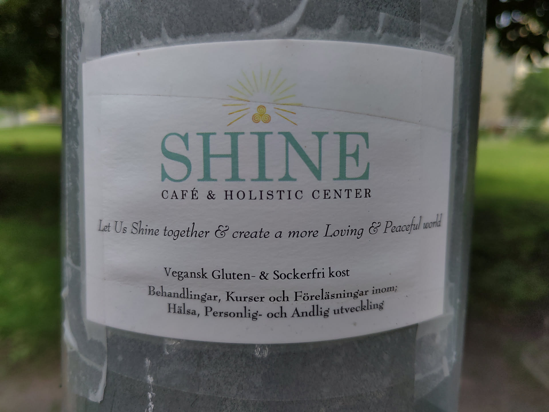 Sticker for Shine Cafe & Holistic Center. The sticker promotes a vegan, gluten and sugar free menu and courses, treatments and lectures within health, personal and spiritual development.