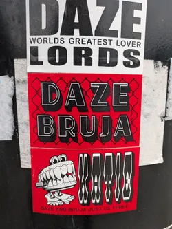 This multi-part sticker is predominantly red and black. The central section displays the words "DAZE BRUJA" in large, black font with a white outline, set against a red background with a black chain-link fence pattern. Below this, another red section features a whimsical illustration of wind-up chattering teeth with prominent eyeballs, positioned next to the word "KATTE" rendered in a striking, distorted black and white font. At the very bottom, in smaller white text, it reads "DAZE AND BRUJA JUST US THREE."