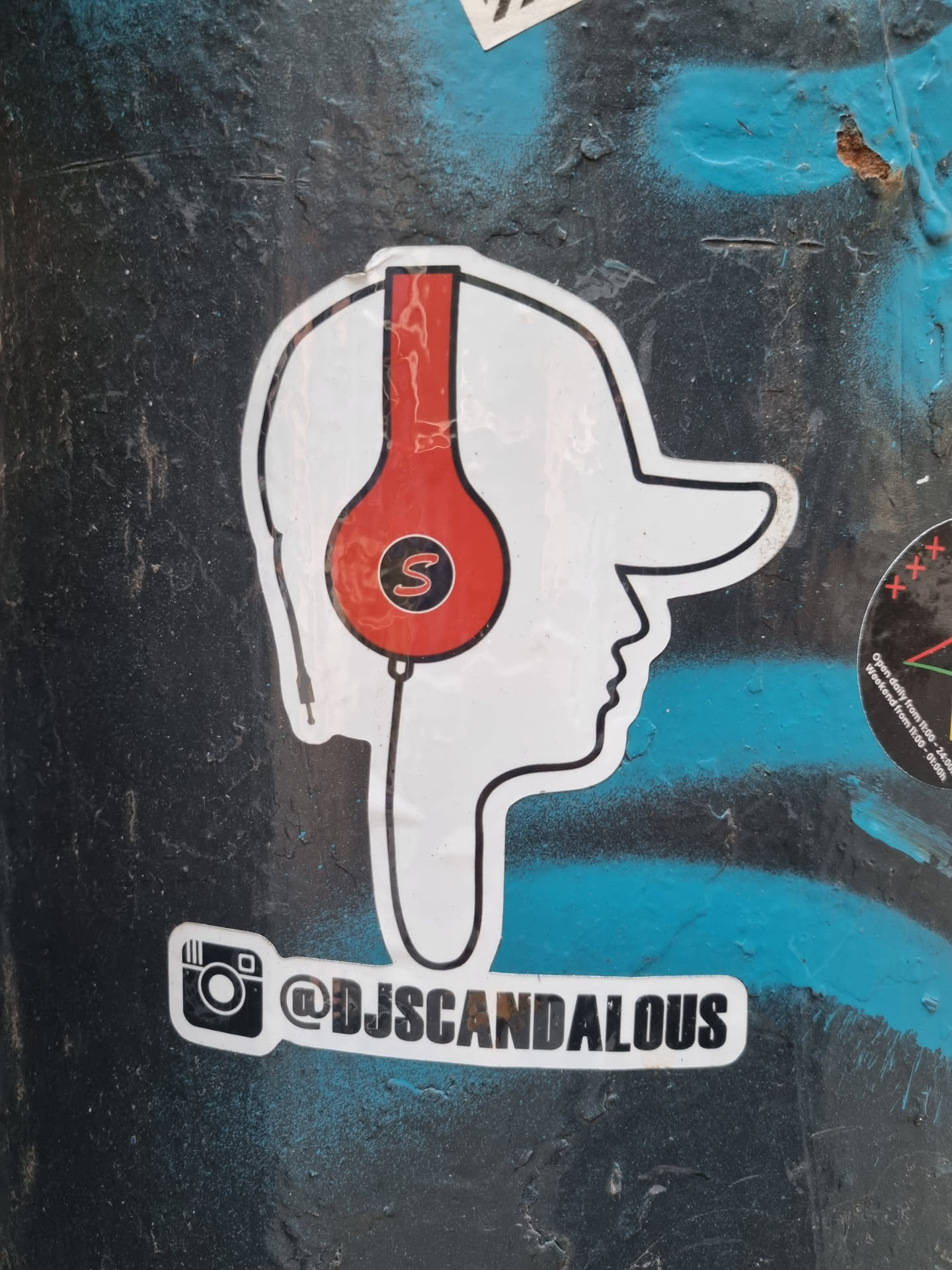 A cool sticker featuring a stylized profile of a person wearing red headphones. The sticker includes the Instagram handle @djscandalous. 