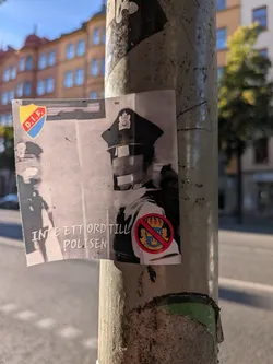 The sticker is a black and white image featuring a person in a police uniform, with their face obscured by horizontal black bars. To the left, the crest of Djurgårdens IF (D.I.F.) is visible, with its yellow, blue, and red colors. On the right side of the police uniform, a red circle with a diagonal line through it is superimposed over the Swedish coat of arms, indicating prohibition. The text 'INTE ETT ORD TILL POLISEN' is printed in white, sans-serif font across the lower portion of the sticker.