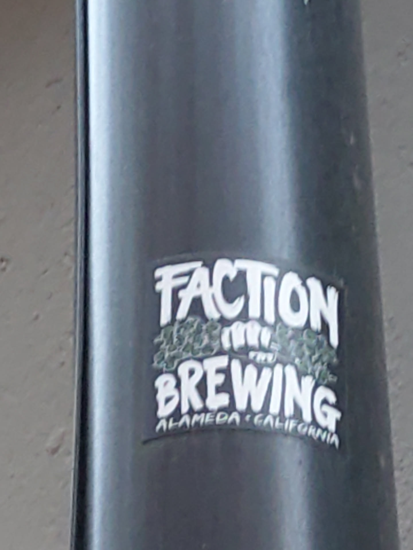 A sticker for Faction Brewing, located in Alameda, California.  The sticker features the brewery's name in stylized graffiti-like lettering with a graphic element that looks like hops.