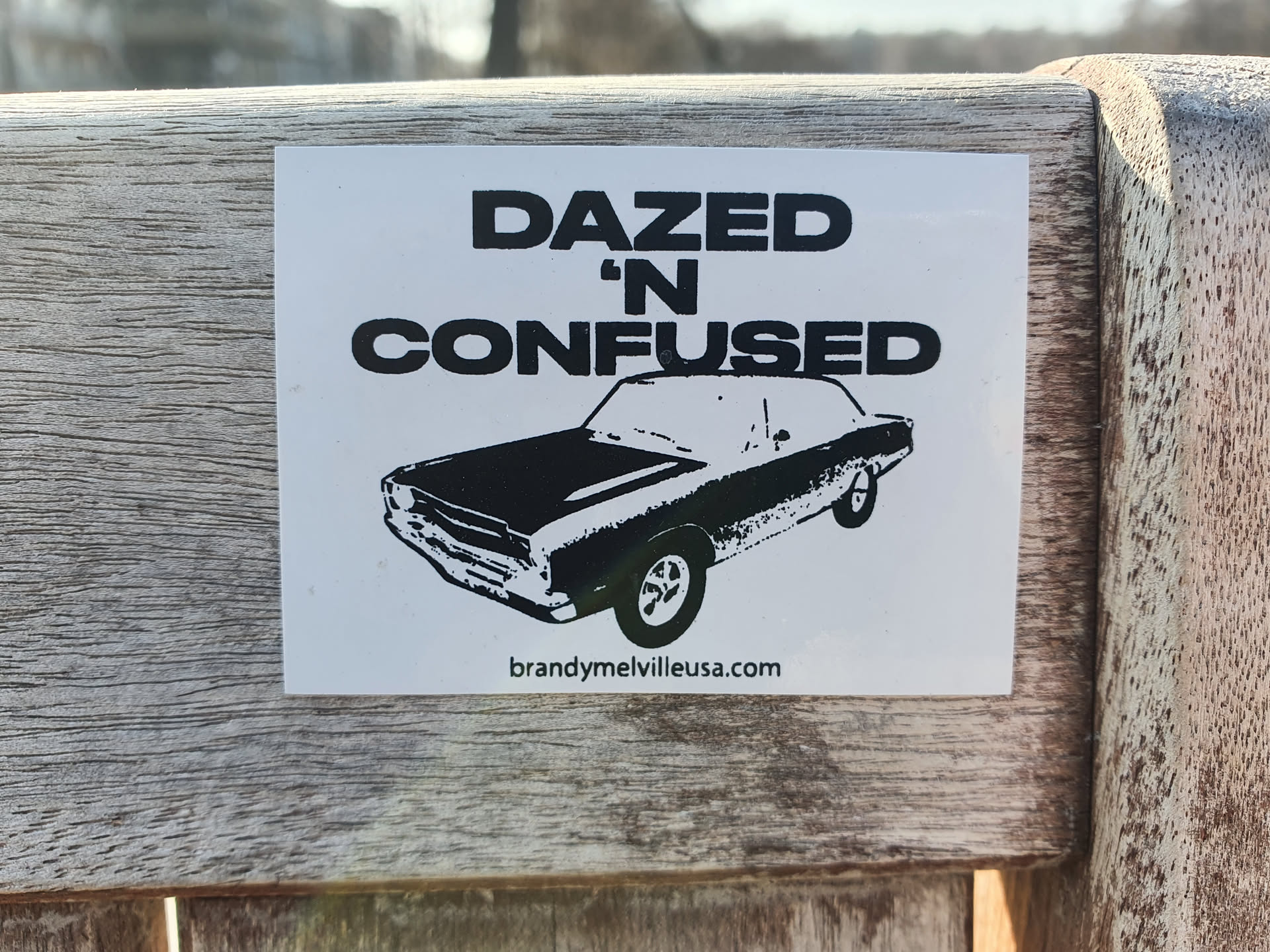 A black and white sticker featuring a vintage car illustration and the text 'Dazed 'n Confused'.  The sticker also includes a website address at the bottom.