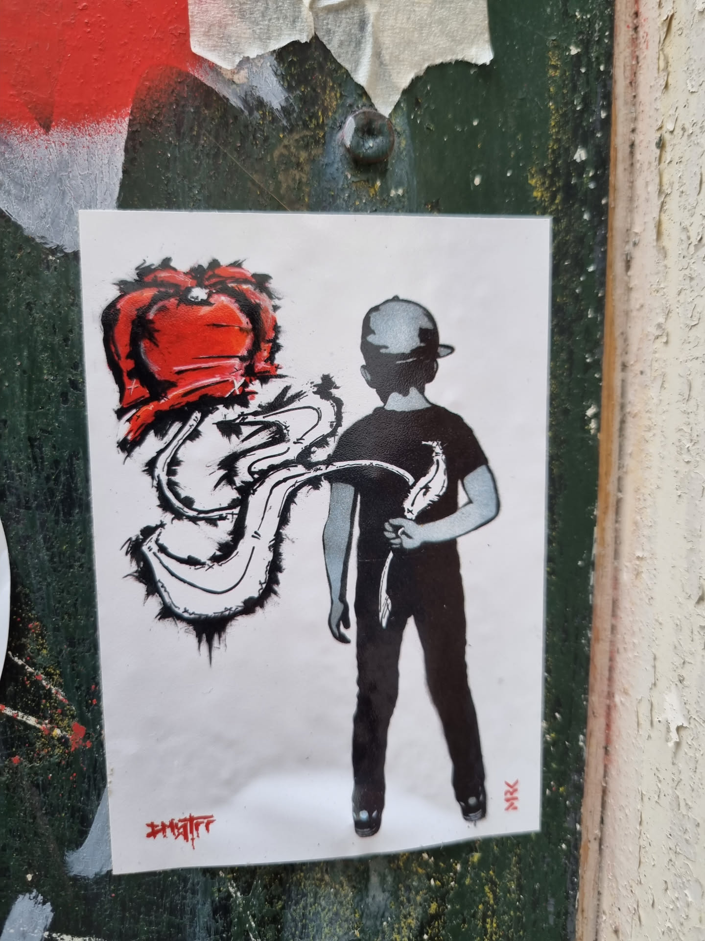This sticker features a stylized illustration of a boy in a cap carrying what seems to be a red heart-shaped object that's creating a flowing trail. The artwork is predominantly in black and red with a simple background.  The style is reminiscent of street art or graffiti.