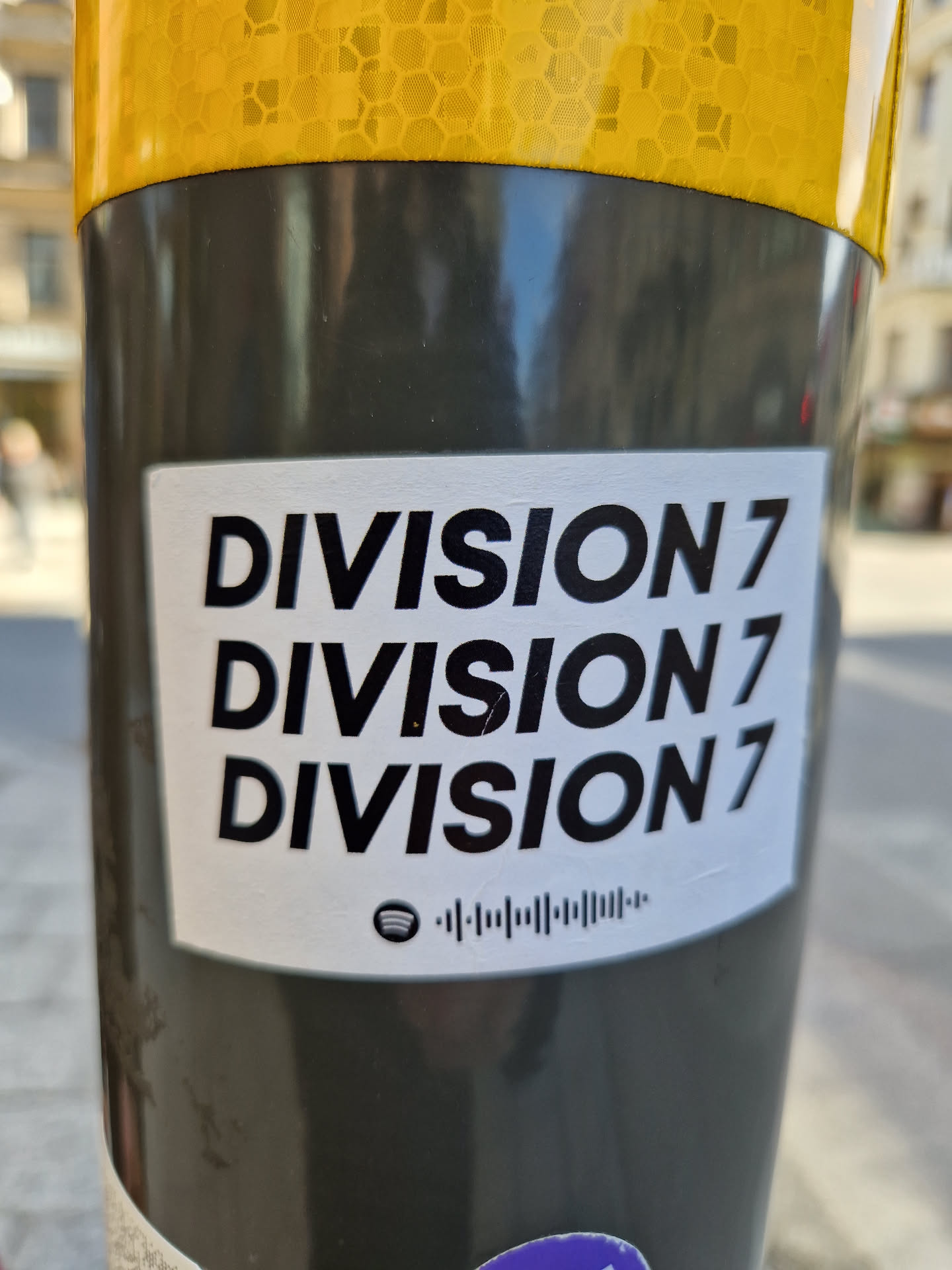 A sticker with the text "DIVISION 7" repeated three times.  It also features a Spotify code at the bottom.