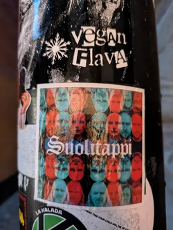 The central sticker is a rectangular, slightly distressed piece featuring a collage of human faces. The faces are rendered in a limited color palette of red and cyan, creating a ghostly, layered effect. They are arranged in a grid-like pattern, with some faces appearing upright and others inverted. The word 'Suolitappi' is prominently displayed in the center in a stylized, gothic-style font with white lettering and a subtle shadow. The overall impression is abstract and slightly unsettling, with a vintage or experimental artistic feel.