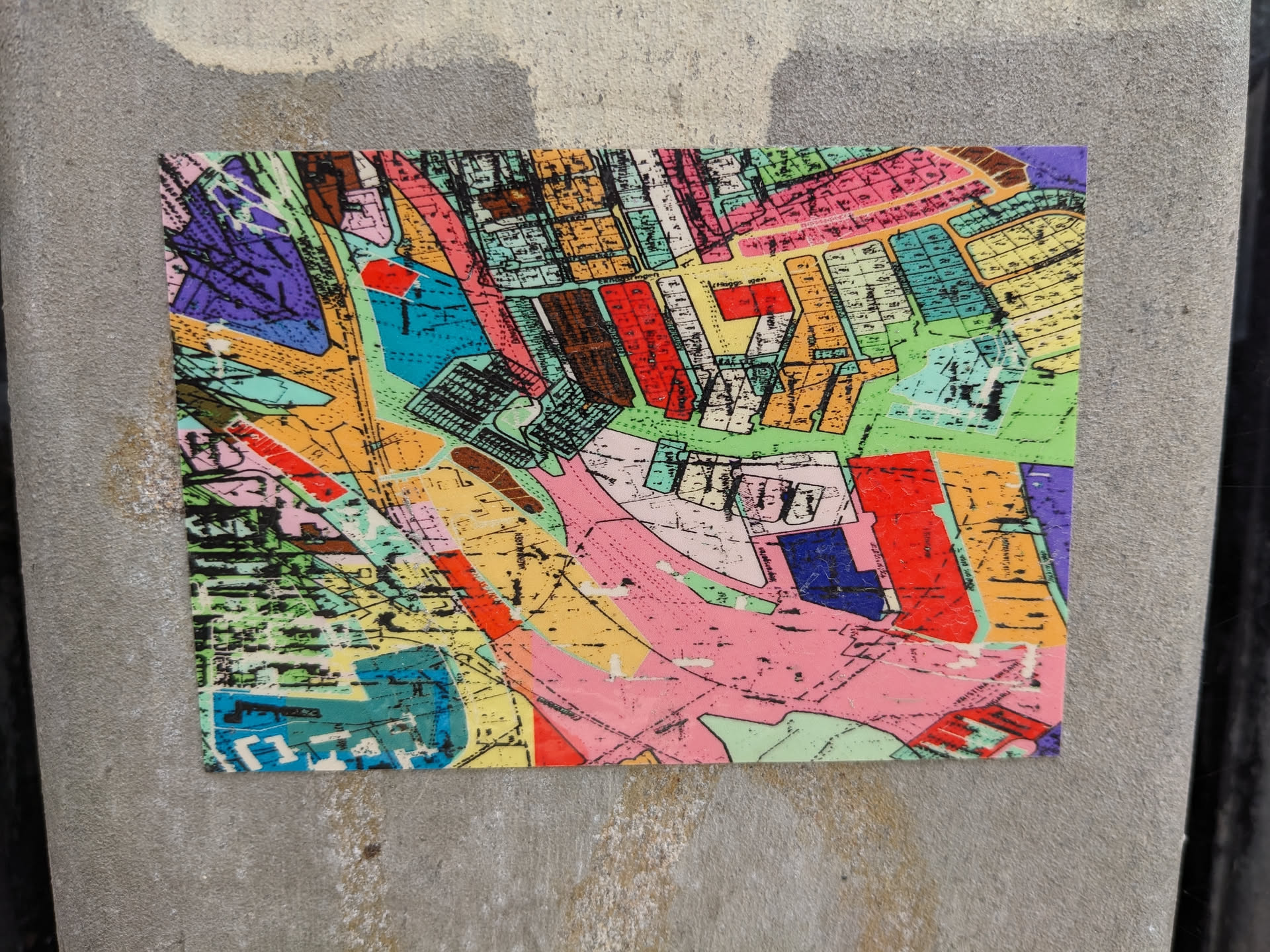 This sticker features an abstract design resembling a map with various colored sections and lines. The style is reminiscent of a collage or a fragmented map view.
