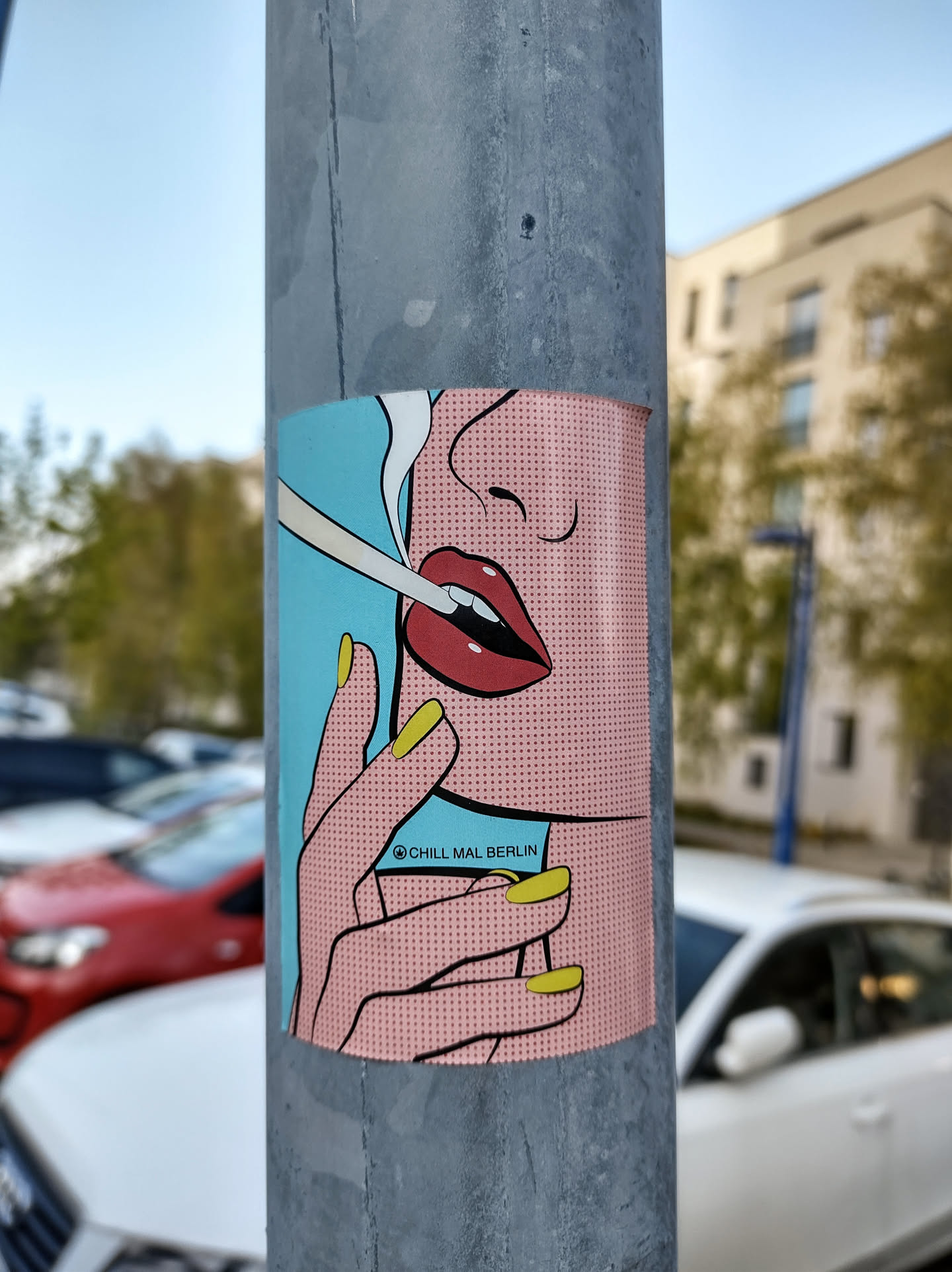 A sticker featuring a pop art style illustration of a woman's face and hand, with red lips and yellow nails. She is holding a cigarette. The sticker has a light blue background and the text "©chill.mal.berlin" is visible.