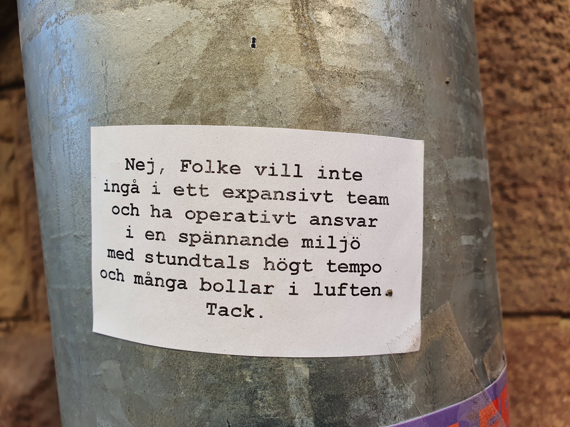 The sticker is attached to a metal pole. The text on the sticker appears to be a polite refusal of a job offer or collaboration.  The tone is respectful and explains the reasons for declining the opportunity.