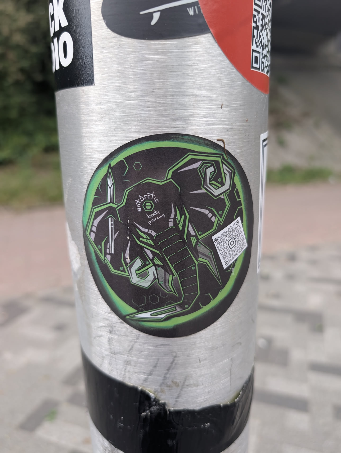 This round sticker displays a stylized elephant design with geometric and neon green accents. The text 'Arctic body piercing' is written on the upper part of the design. There's also a QR code that leads to their Instagram.
