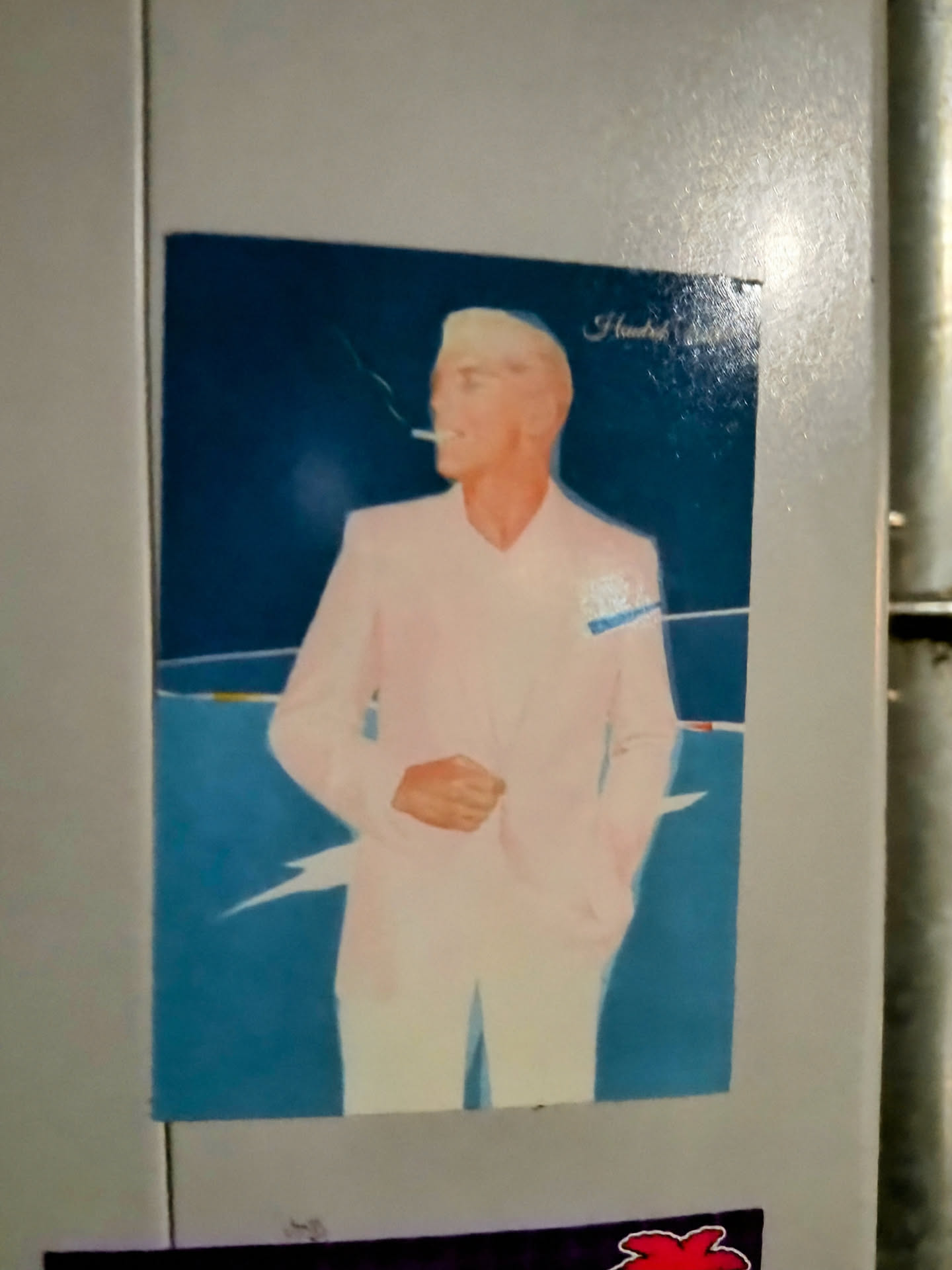This sticker shows a painting or illustration of a man with blond hair, wearing a light pink suit, smoking a cigarette. The background is teal, with some light lines suggesting a beach or sea shore. The style seems to be retro or vintage.  The upper right corner shows the word "Handel" written in small letters.