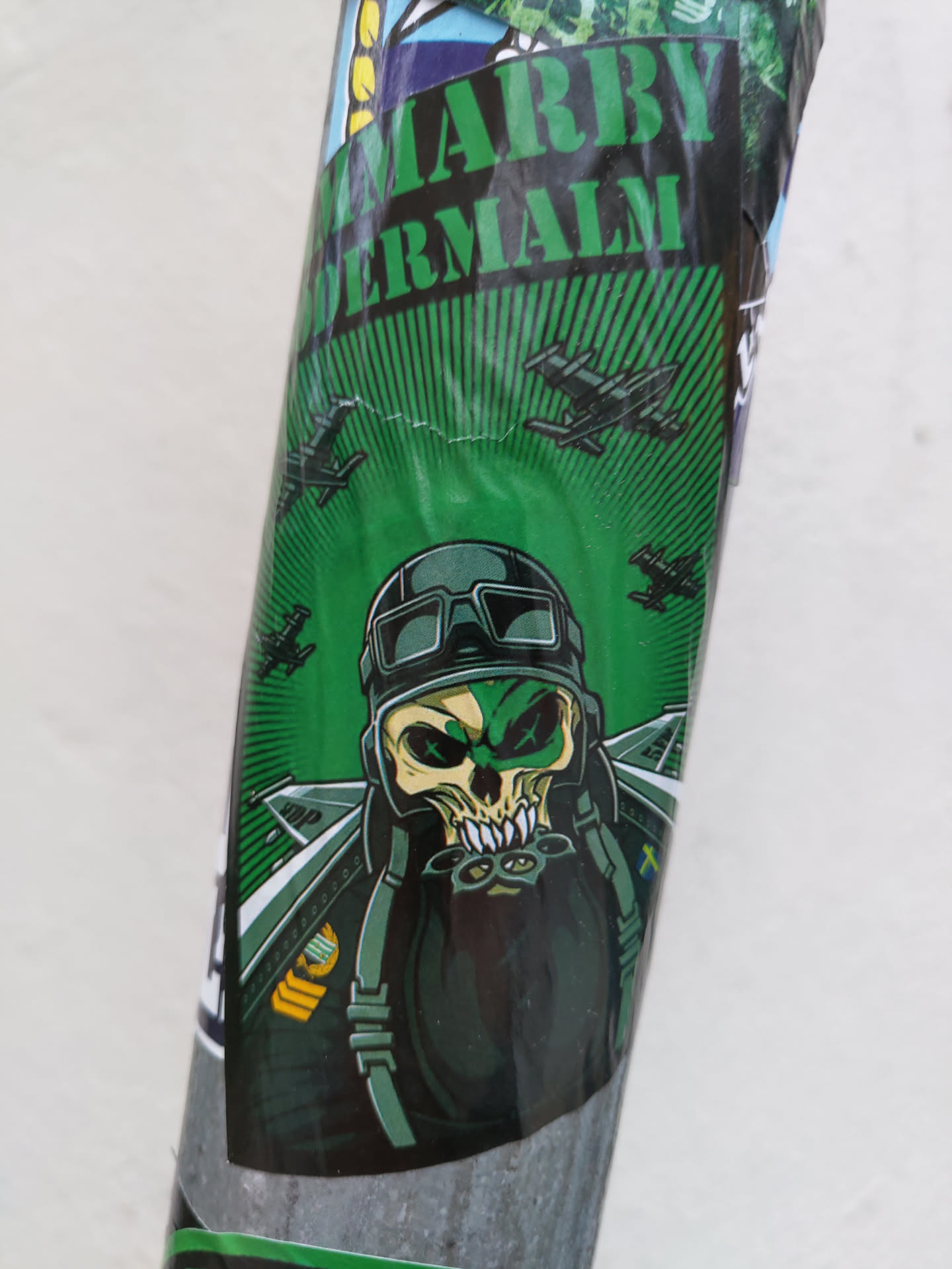 A green sticker featuring a skull wearing a pilot's helmet and goggles.  Airplanes are depicted in the background. The top of the sticker shows some text that looks like "MARRY DERMALM".