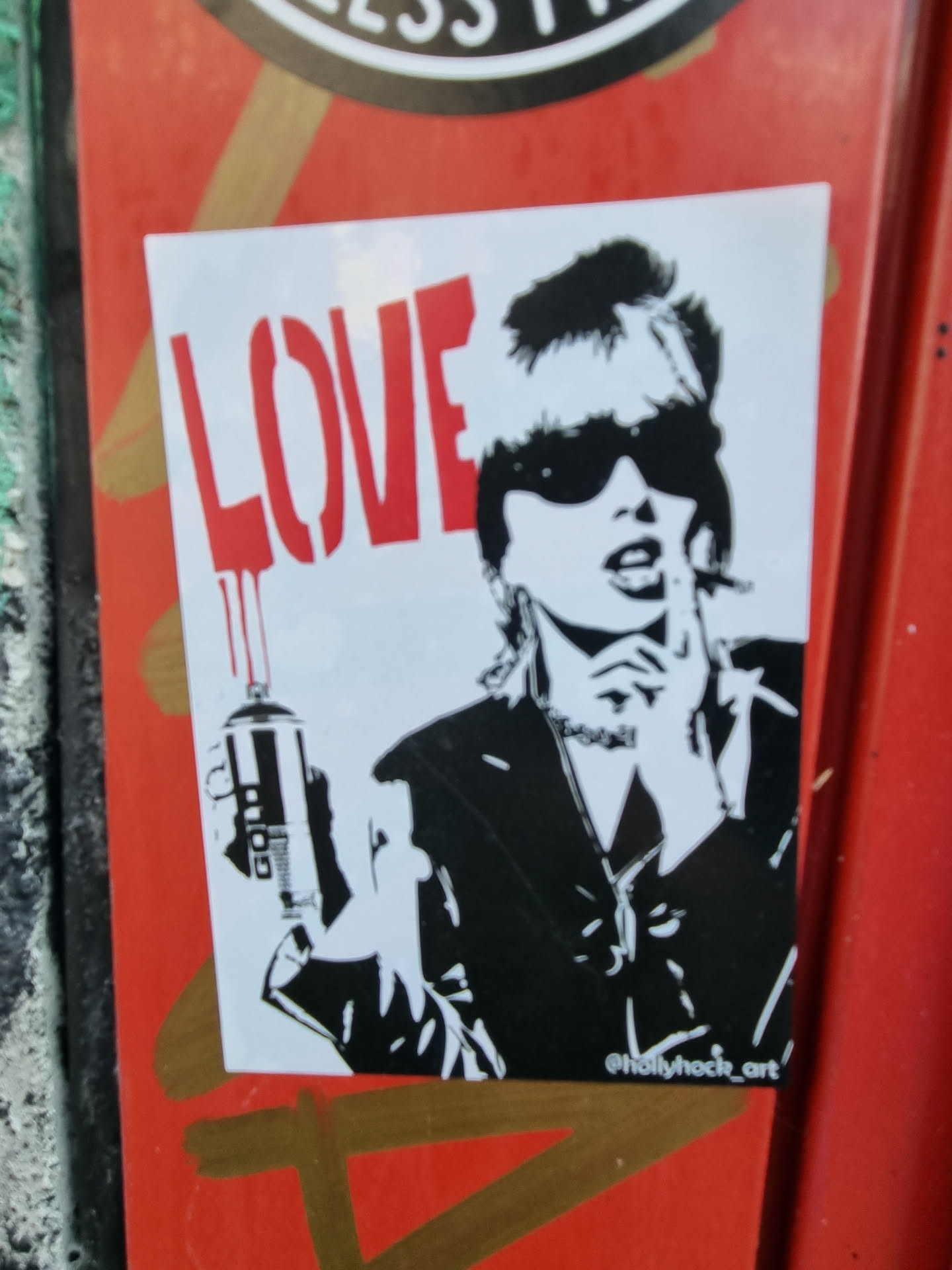 Black and white sticker featuring a stylized woman holding a spray can with the word LOVE painted in red dripping down the can.