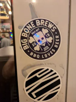 A round sticker featuring the logo of Big Bone Brews, a brewery.  The logo includes a skull design with crossed bones, text that says "Big Bone Brews" and "BBQ Loves Beer." There is also some smaller text indicating a "2019 BBQ-Off".