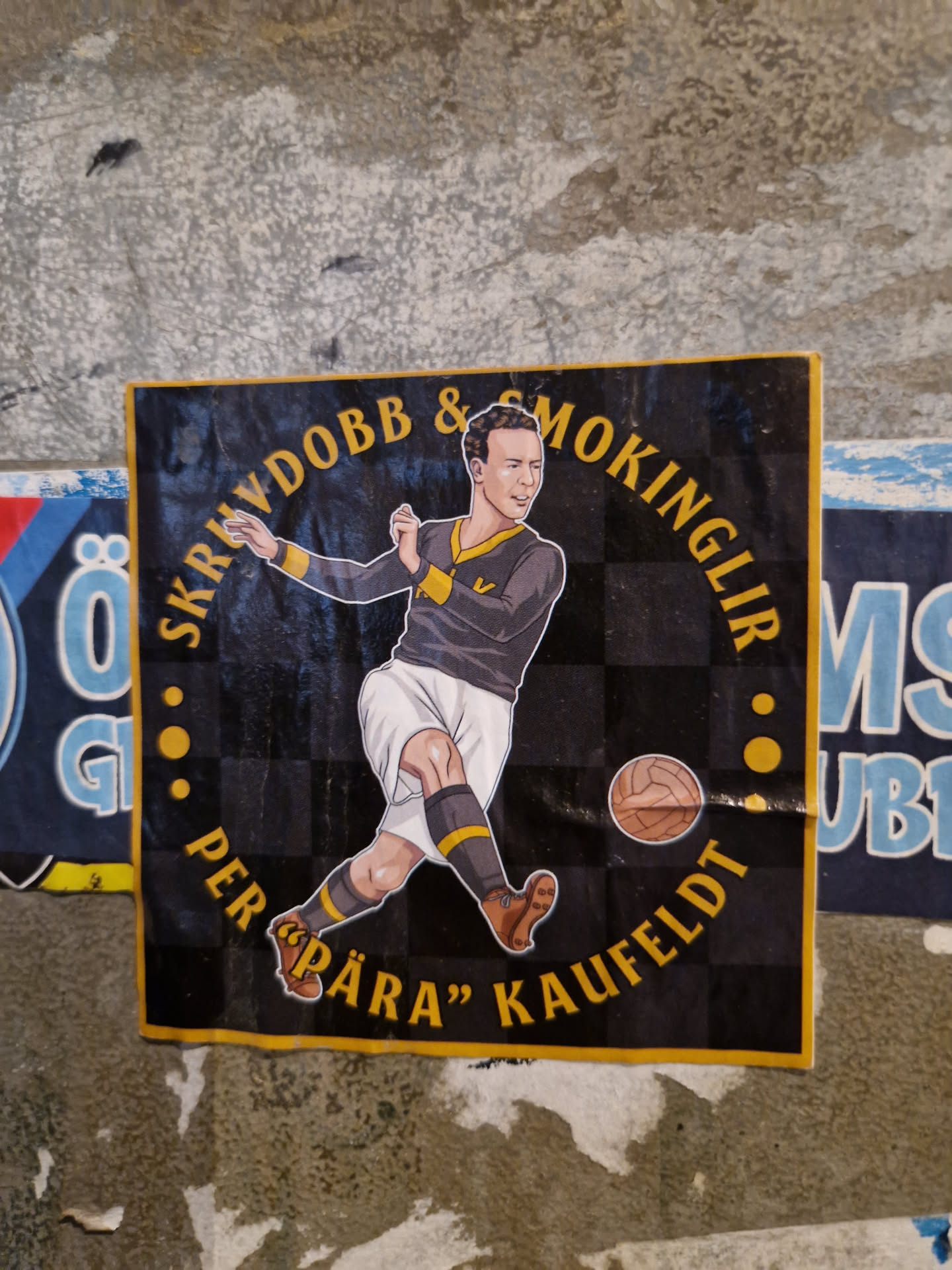 A sticker featuring an illustration of Per "Påra" Kaufeldt, a soccer player, with text that says "Skryddobb & Smokinglir" around the illustration. The background is a checkered pattern.