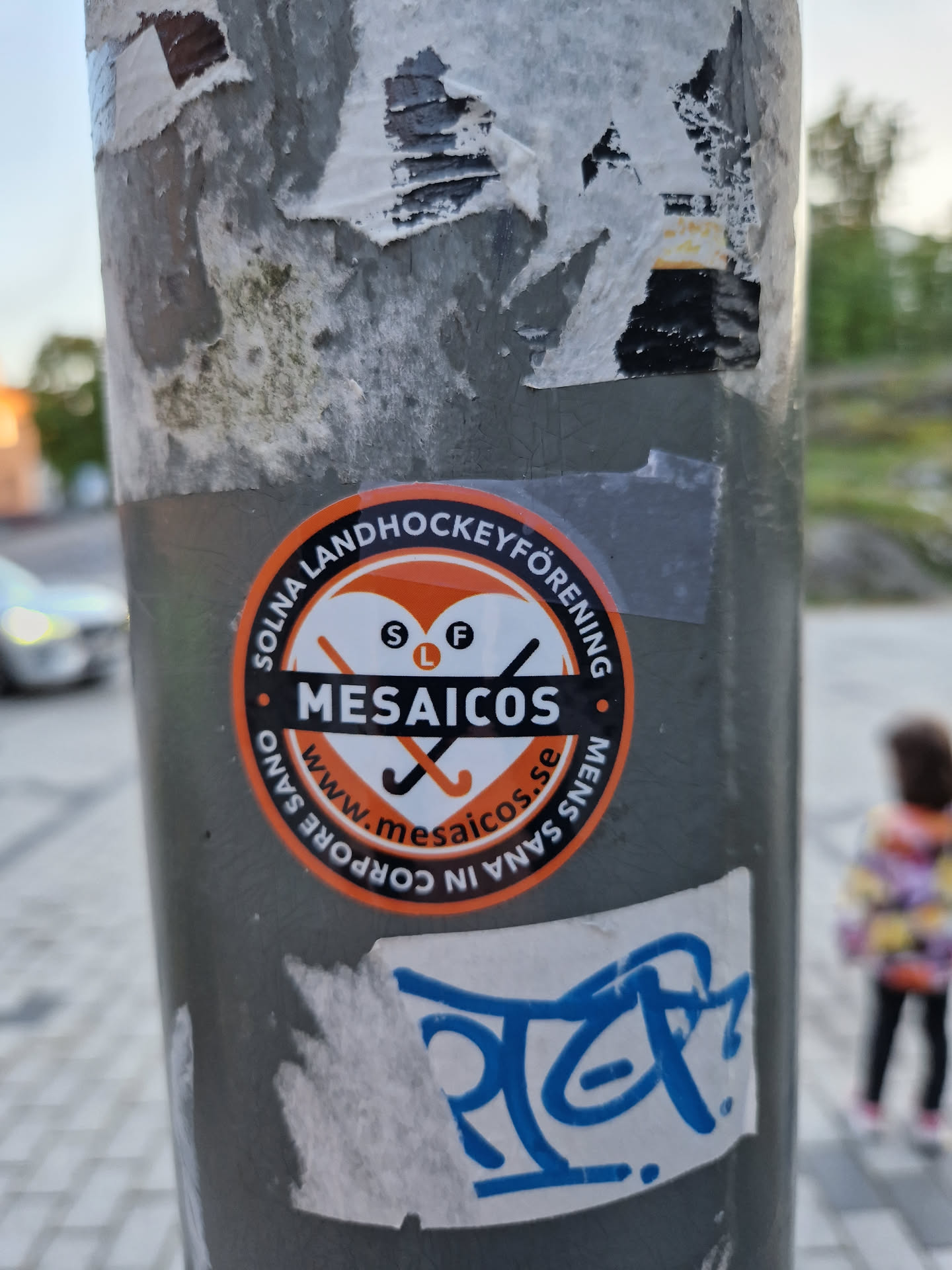 Round orange and white sticker with the text "Solna Landhockeyförening" and the logo of Mesaicos.  The website www.mesaicos.se is also on the sticker.