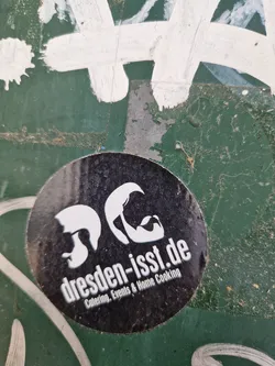 Round black and white sticker with the text "dresden-isst.de" and the description "Catering, Events & Home Cooking".  It also features two stylized faces.