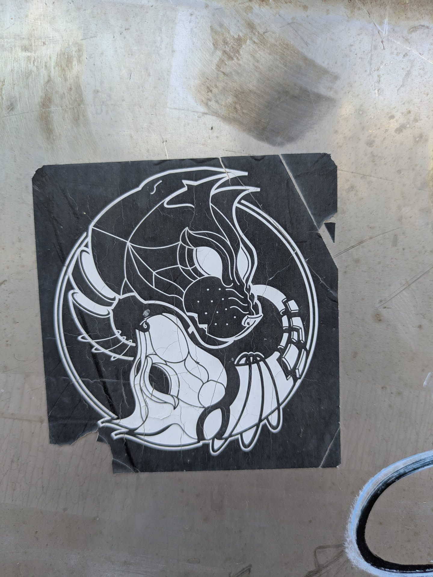 This sticker depicts a black and white design in the style of a yin-yang symbol. On one side, there's a wolf with sharp features and intricate details. On the other side, there's a lamb with similar design elements. Both are contained within a circular border on a black background.