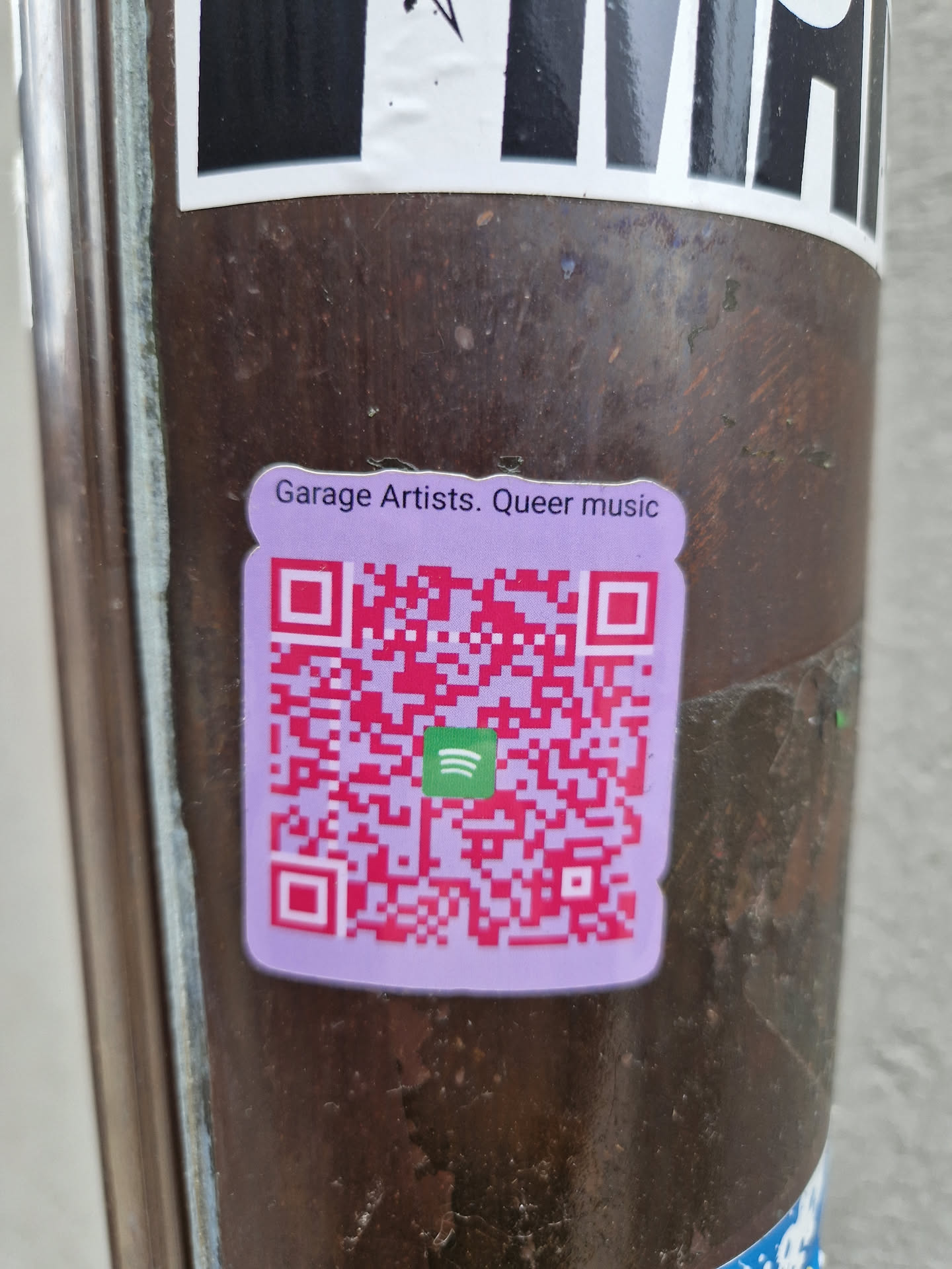 A purple sticker with a QR code leading to a Spotify playlist. The text on the sticker reads "Garage Artists. Queer music".