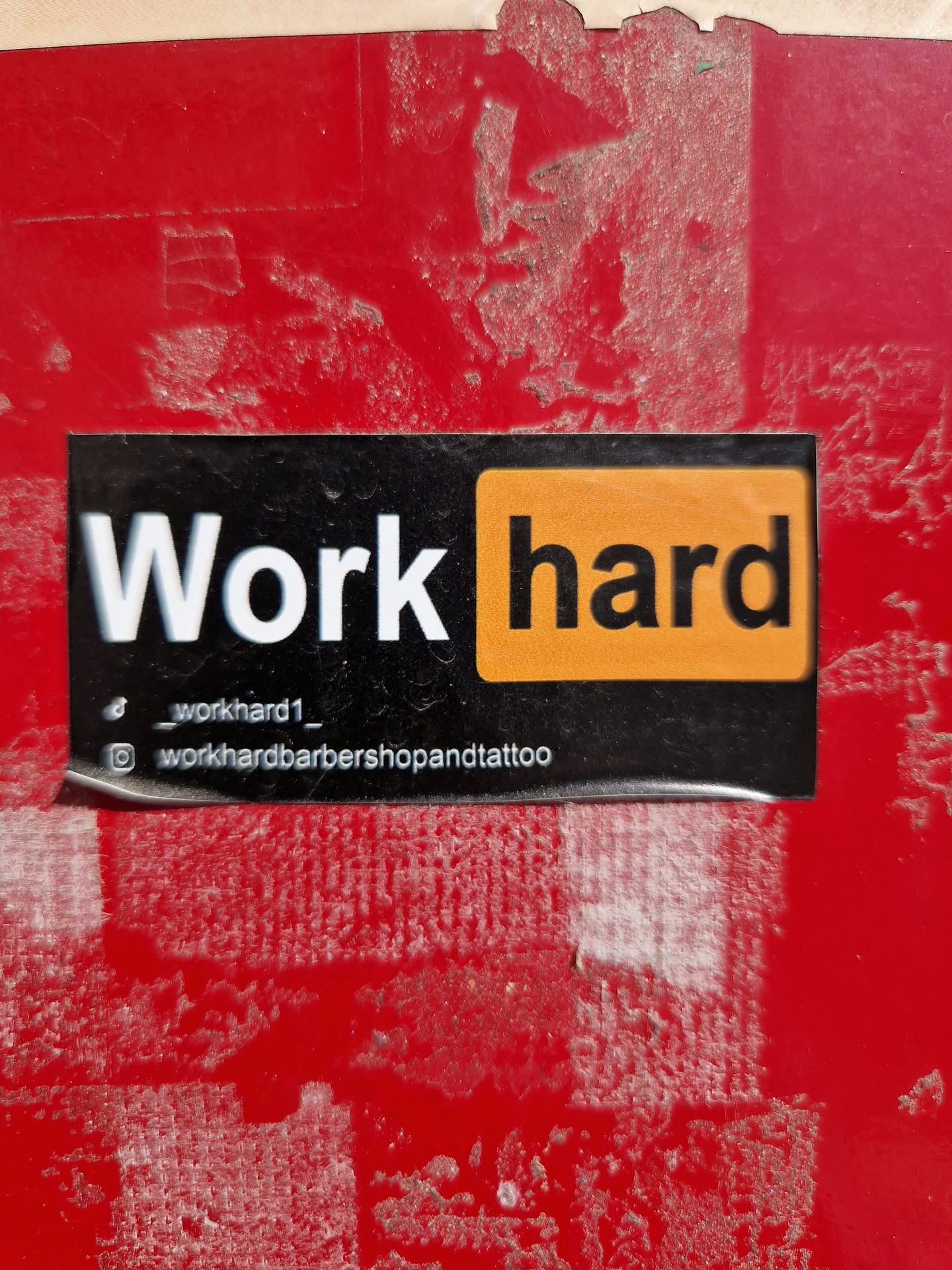 Black and orange sticker with the text "Work hard" and social media handles.