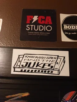 A sticker featuring a hand-drawn illustration of a harmonica with the band's name written above it. The art style is simple and slightly rough, giving it a handmade feel. The sticker is white with black ink.